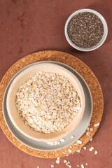 A healthy breakfast featuring oats in a bowl on a cork mat, accompanied by chia seeds, showcasing a rustic and wholesome meal