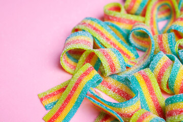 Tasty rainbow sour belts on pink background, closeup. Space for text
