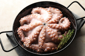 Fresh raw octopus and thyme in frying pan on grey table, closeup