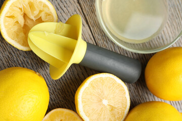 Plastic juicer and fresh lemons on grey wooden table, flat lay