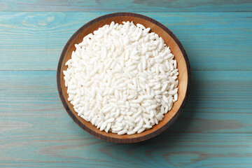 Puffed rice in bowl on light blue wooden table, top view