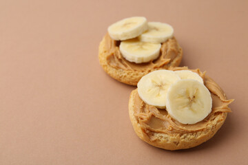 Tasty sandwiches with peanut butter and banana on brown background, closeup. Space for text