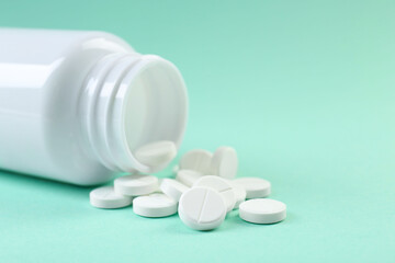 Bottle of antibiotic pills on turquoise background, closeup. Space for text