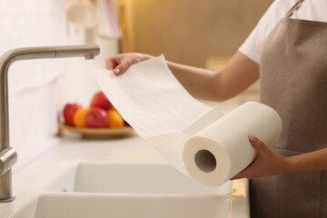 Woman using paper towels above sink in kitchen, closeup