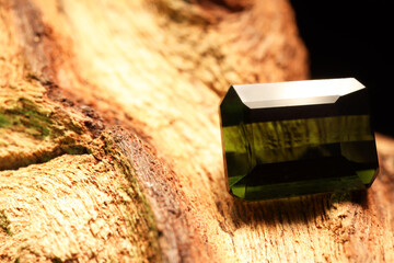 Beautiful shiny green gemstone on stone, closeup. Space for text