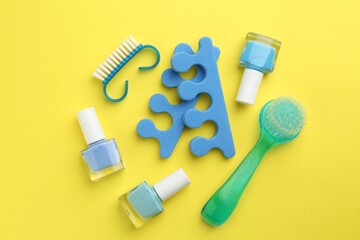 Set of pedicure tools on yellow background, flat lay