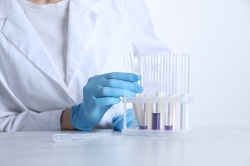 Laboratory testing. Scientist working with test tubes at white marble table, closeup