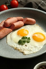 Tasty fried eggs and sausages served on table, closeup