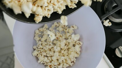 Serving fresh homemade popcorn into a bowl. - Powered by Adobe