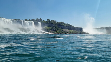 Niagara Falls. A pleasure boat with people near the huge famous waterfall. View from the Canadian side. Nature scenery. Photo for advertising