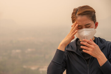 Asian woman having headache becaused of by Bad air pollution (PM2.5).