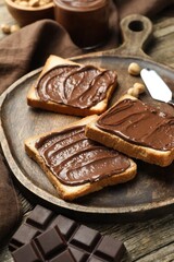 Tasty sandwiches with chocolate butter and pieces of chocolate on table, closeup