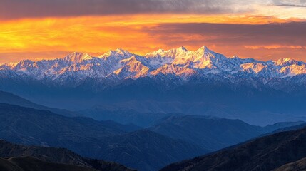 Obraz premium Sunrise over the Himalayas, golden rays illuminating snow-capped peaks, rugged terrain glowing warmly, sky shifting from deep blue to fiery orange.
