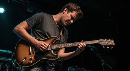 Caucasian young male guitarist playing electric guitar on stage under stage lights
