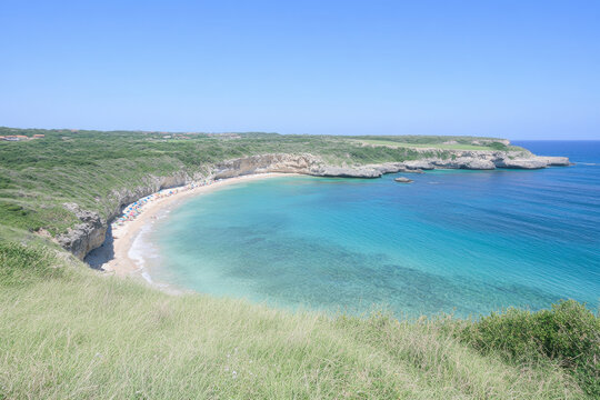A beach with a blue ocean and a green hillside