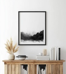 A minimalist black and white mountain landscape artwork in a sleek frame, displayed above a wooden shelf with decorative items.