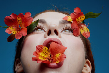 Woman with flowers in her mouth, vibrant colors, blue background, emotional expression, nature...