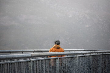 woman orange jacket hat lookout mist winter cold fog