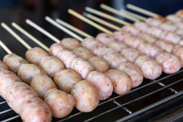northeastern sausage on stick or skewered and arranged grilled burn on charcoal stove or isan sausage and rare barbecue meatball for traditional thai street food in local thailand or esan sausages