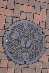 ひまわりとケヤキの葉が描かれている大府市のマンホールの蓋