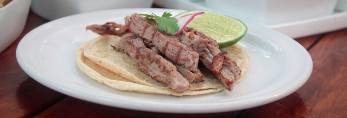 Close-up of a gourmet arrachera (flank steak) taco showcasing tender grilled beef, fresh cilantro, and radish slices inside a soft corn tortilla.