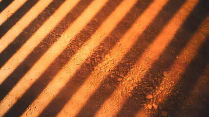 Sunbeams and Striations: An abstract design of parallel shadows cast upon a textured, earthy surface, illuminated by a warm, golden glow of sunlight.  
