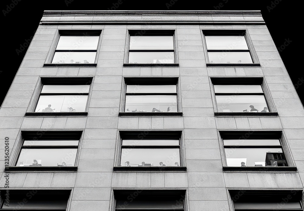 Poster low angle view of a multi story building with numerous windows, rendered in grayscale. the building'
