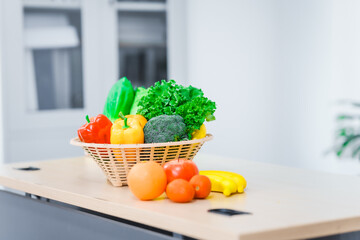 A nutritionist's table neatly arranged with a basket overflowing with fresh vegetables and fruits, including lettuce, kale, bell peppers, bananas, onions, and tomatoes, health and nutrition.