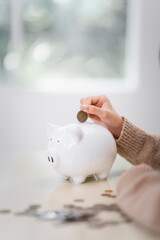 11-year-old Asian girl, wearing light brown sweater, holds piggy bank, importance of saving. encourages money management, saving habits, preparing for future financial goals.