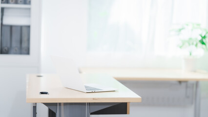 Blank white laptop on blank office desk with blurry white background for display your ads.