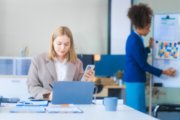 Obraz premium A young Russian woman in formal suit works diligently in business office, analyzing financial charts, using a desktop PC, calculator while contributing to various business strategies and projects.