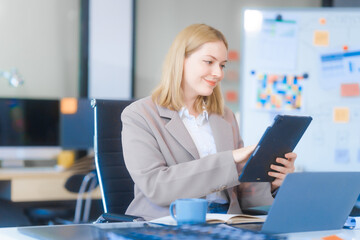 A young Russian woman in formal suit works diligently in business office, analyzing financial...