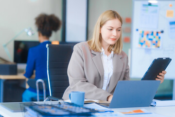 A young Russian woman in formal suit works diligently in business office, analyzing financial...