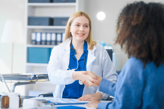 A young African American patient consults with a young Russian medical doctor about her immune system and vitamin intake. They discuss patient medical history,  vitamin and pill bottles on the desk.