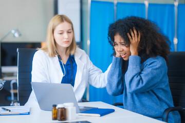 A young African American patient consults with a young Russian medical doctor about her immune system and vitamin intake. They discuss patient medical history,  vitamin and pill bottles on the desk.