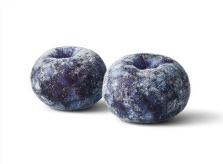 Fototapeta premium Two dark blue plums, dusted with a light layer of sugar or frost, are photographed against a bright white background. The plums are round and plump