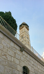 Fototapeta premium View from Church of the Holy Sepulchre yard to tall stone minaret of Mosque of Omar in Jerusaslem old city in Israel