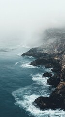 Fototapeta premium Serene Coastal Landscape Under Fog with Gentle Waves and Rocks