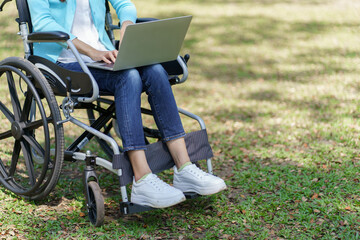 Young asian woman in wheelchair working with laptop