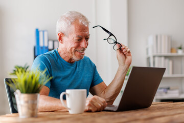 Fototapeta premium Overjoyed middle-aged man at home desk talk on video call on modern laptop, happy excited senior male greeting speak on web using laptop, technology concept