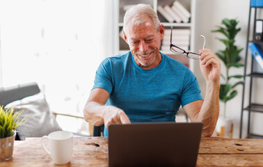 Overjoyed middle-aged man at home desk talk on video call on modern laptop, happy excited senior male greeting speak on web using laptop, technology concept