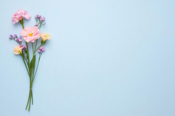 Fototapeta premium Top-down shot of a tiny bouquet of mixed flowers, pastel backdrop, open space above for branding or message placement