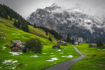 Scattered alpine wooden huts and misty snowy mountains in Switzerland