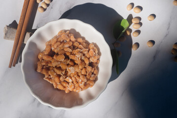 Natto fermented soy bean in white ceramic bowl on marble background.