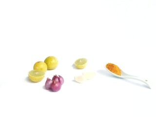 Kitchen spices, ground turmeric, three limes and garlic and shallots on a white background