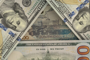Kazakhstani tenge banknote peeks out from under US dollar bills. Currency market. Finance concept