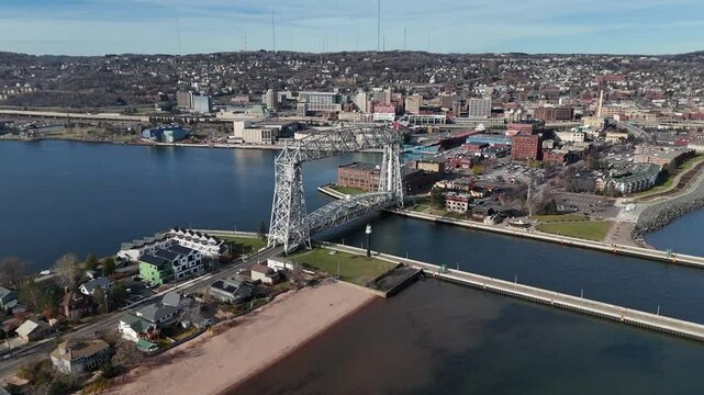 Aerial View, Slowly panning around Aerial Lift Bridge in Duluth Minnesota as cars drive across. businesses, hotels and resorts in background. Late Fall with partly cloudy skies.