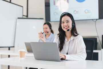 smiling customer service representative wearing headset works on laptop in modern office