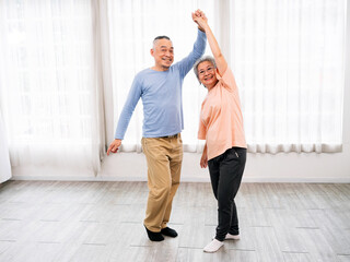 Fototapeta premium Joyful senior couple dances together in bright room, embracing love, companionship, and active aging. They enjoy retirement, active, and aging gracefully. Sharing laughter, wellness, and togetherness.