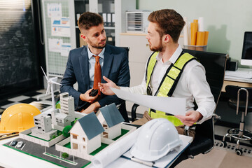 Engineering team collaborates on blueprint and project planning. Strategic partnership and innovation drive successful model development in a corporate office setting.